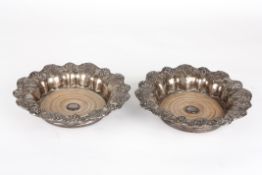 A large pair of silver plated bottle coastersthe lobed rims decorated with grapes and vine