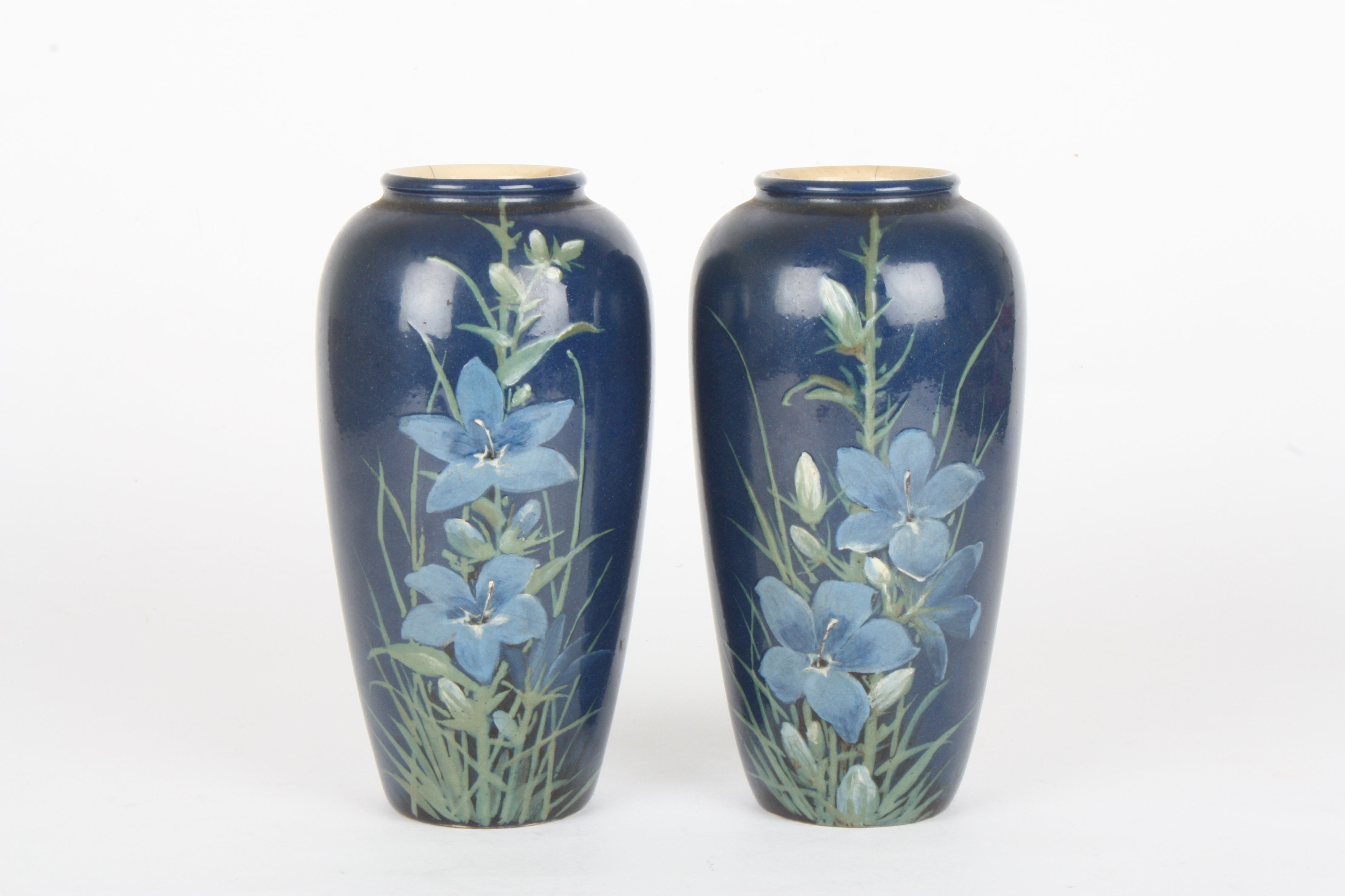 A pair of Royal Doulton Faience vases by Florence Barlow
decorated with flowers and leaves on a