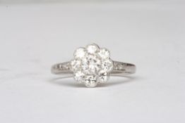 A white gold and diamond daisy cluster ringthe central stone weighing approx 0.23cts, surrounded by