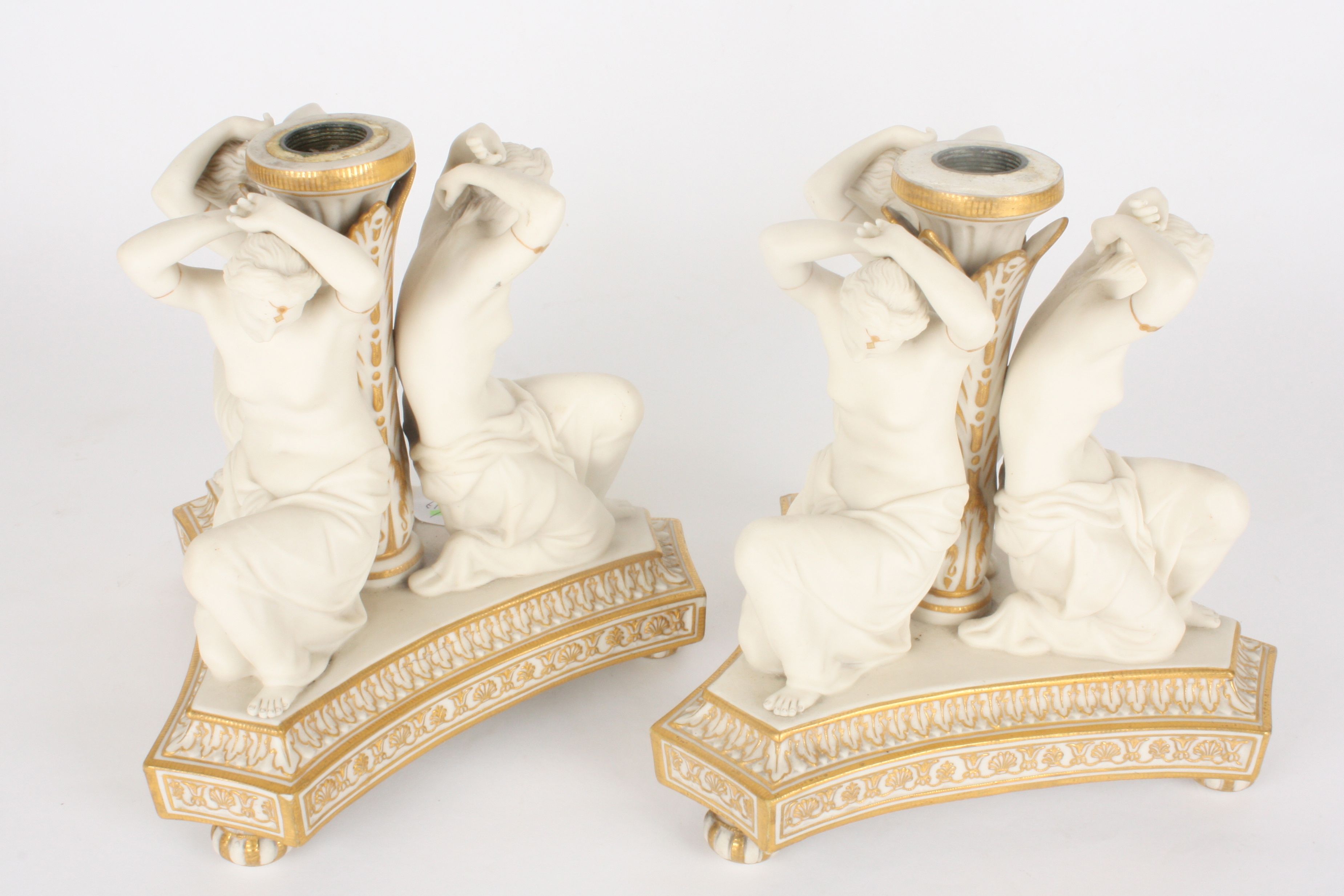 A pair of Victorian Copeland parian three graces candlesticks
formed as three kneeling semi-nudes