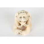 An early 20th century Japanese carved ivory netsuke
formed as a seated monkey holding his hands to