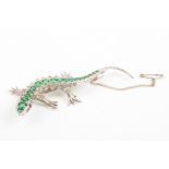 A costume jewellery lizard brooch
with a row of green paste stones down her back, flanked by rows of