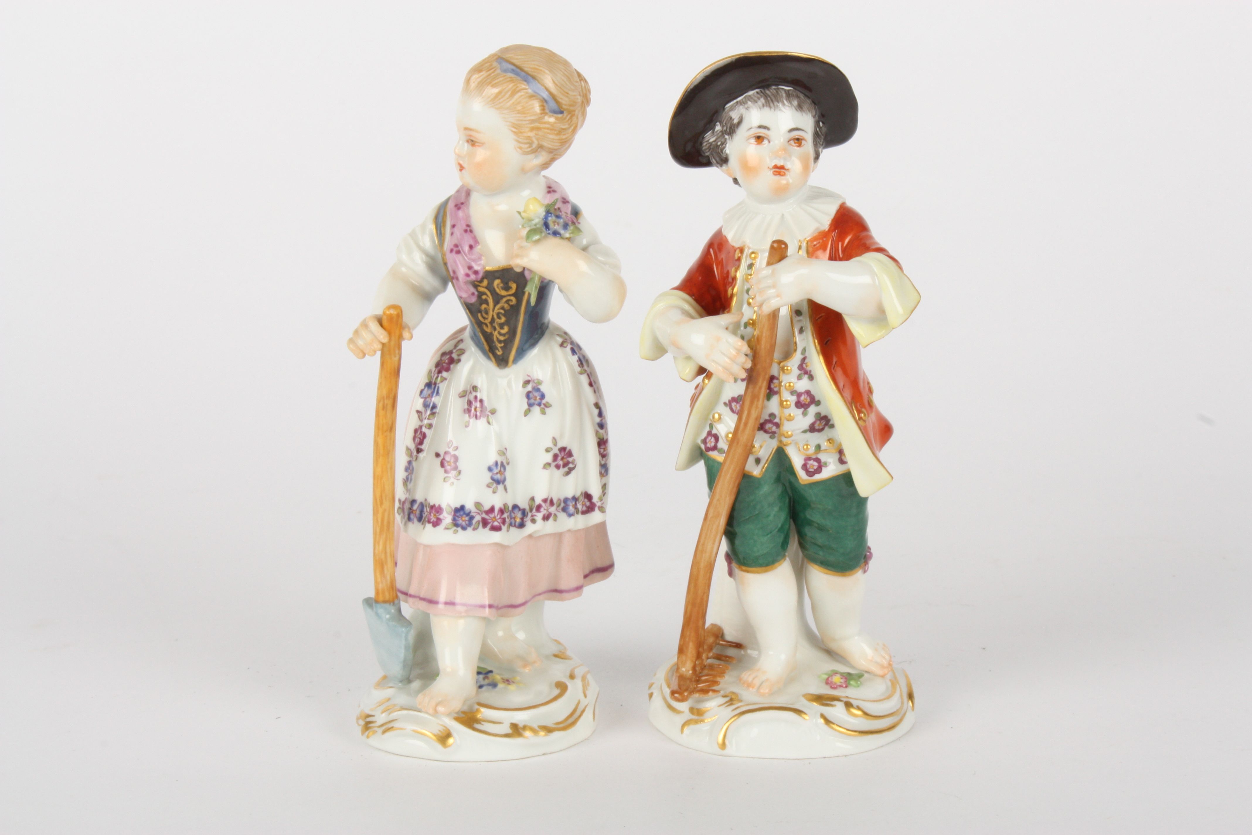 Pair of Late 20th century Meissen figures modelled as a gardening boy holding a rake and girl