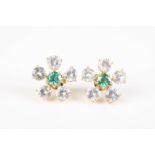 A pair of white sapphire and emerald flower head earrings
each set with a central emerald weighing
