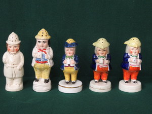 FOUR STAFFORDSHIRE HANDPAINTED FIGURE FORM PEPPER POTS AND ONE OTHER SIMILAR PEPPER POT BEARING