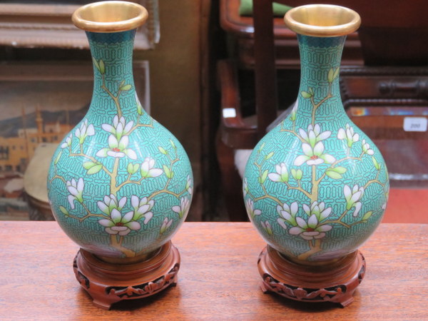 PAIR OF FLORAL DECORATED CLOISONNE VASES ON CARVED PIERCEWORK TREEN STANDS,