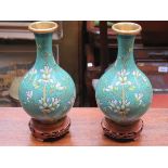 PAIR OF FLORAL DECORATED CLOISONNE VASES ON CARVED PIERCEWORK TREEN STANDS,