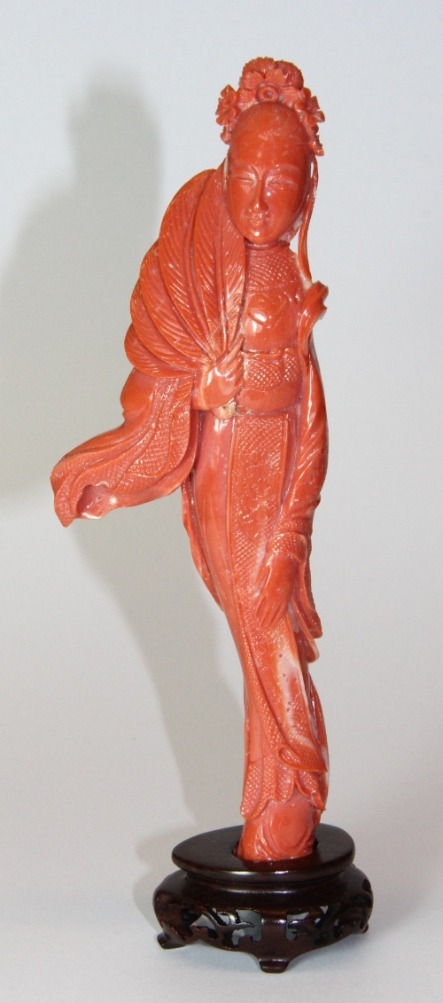 A very fine Chinese carved natural pink coral figure of a young woman with hardwood stand H 17cm