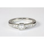 A heavy platinum ring set with a princess cut centre diamond and further princess cut diamonds to