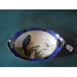 A Noritake  oval dish, painted with parrots on an ivorine ground, within a scale border, 29.5cm
