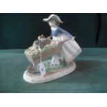 A Lladro figure modelled as a young girl with a wheelbarrow and two puppies, 22cm high.