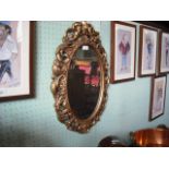 A wall mirror, the oval plate in an 18th century-style hardwood giltwood frame.