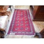 A woollen carpet with geometric designs on a red ground,