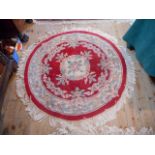 A circular contemporary Chinese rug with floral decoration throughout on a red ground,