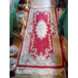 A contemporary Chinese rug with central floral panel on red ground,