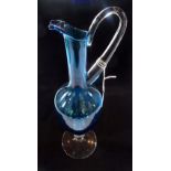 A tall Whitefriars-style glass ewer, in kingfisher blue with clear handle, column and circular base,