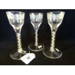 A set of three wine glasses with engraved funnel bowls on stems,