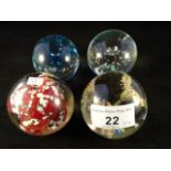 A collection of four glass paperweights.