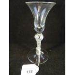 A mid-18th century wine glass with bell shaped bowl on a knopped air-drawn stem, 17cm high.