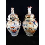 A pair of Japanese Imari vases and covers, each typically decorated with flora and fauna,