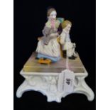 A Continental ceramic inkstand, circa 1890, having a bisque figural group to cover,