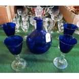 A blue glass single handed decanter, together with four matching wine glasses.
