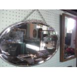 An oval bevelled edge glass wall mirror in metal frame, together with another, rectangular,