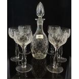 A cut glass decanter with tulip shape stopper, together with six tall stemmed wine glasses.