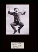 Sir Norman Wisdom. Signature with classic picture. Professionally mounted in black to 16”x12”.