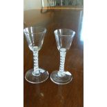 Two similar 18th century opaque twist wine glasses, the rounded conical bowls on double helix