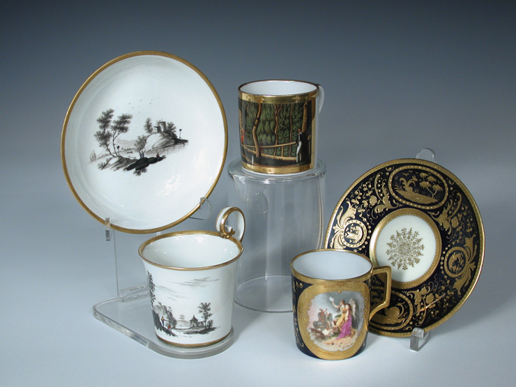 Two Vienna coffee cans and saucers and a German can, the first painted in black with figure by a