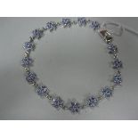 A 9ct white gold line bracelet with floral clusters, each cluster of pale lilac hardstones