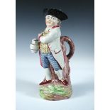 An early 19th century Hearty Good Fellow Toby jug, he stands by a tree trunk a branch of which forms