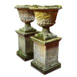 A pair of weathered Haddon Stone garden urns, each on a square pedestal plinth 113 x 64cm (44 x