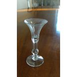 An 18th century wine glass with a tear below the tumpet bowl and knop to the clear stem, 15.5cm (6.