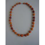 A vintage butterscotch amber bead necklace, the opaque oval beads of variable colour, consistency