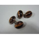 A pair of double-ended tiger's eye cufflinks, each end an oval cabochon tiger's eye in closed back