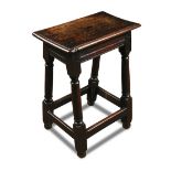 A 17th century oak stool, with plain moulded frieze and on column legs 59 x 46 x 26cm (23 x 18 x