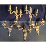 A set of four 20th century gilt metal wall lights, each with a pair of foliate nozzles scrolling