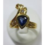 An 18ct gold asymmetric tanzanite and diamond ring, the reeded ribbon band terminating at one end