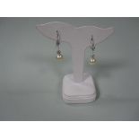 A pair of diamond earrings with removable diamond and pearl drops, each hook terminating to the