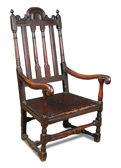 A Carolean oak armchair, with shaped crest rail, turned rail and slat back, scrolling arm