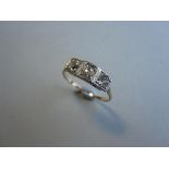 An art deco three stone diamond ring, the graduated old cut diamonds, two cushion one round, in