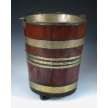 An 18th century brass bound mahogany peat bucket, of tapering cylindrical form raised on three