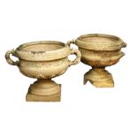A pair of yellow stoneware urns attributed to Blashfield, each with two handles, on square plinth