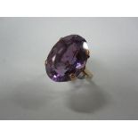 A single stone amethyst dress ring, the large oval cut amethyst in a four claw setting to plain