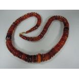 An amber bead necklace, composed of graduated discs of varying thickness, colour and opacity, many