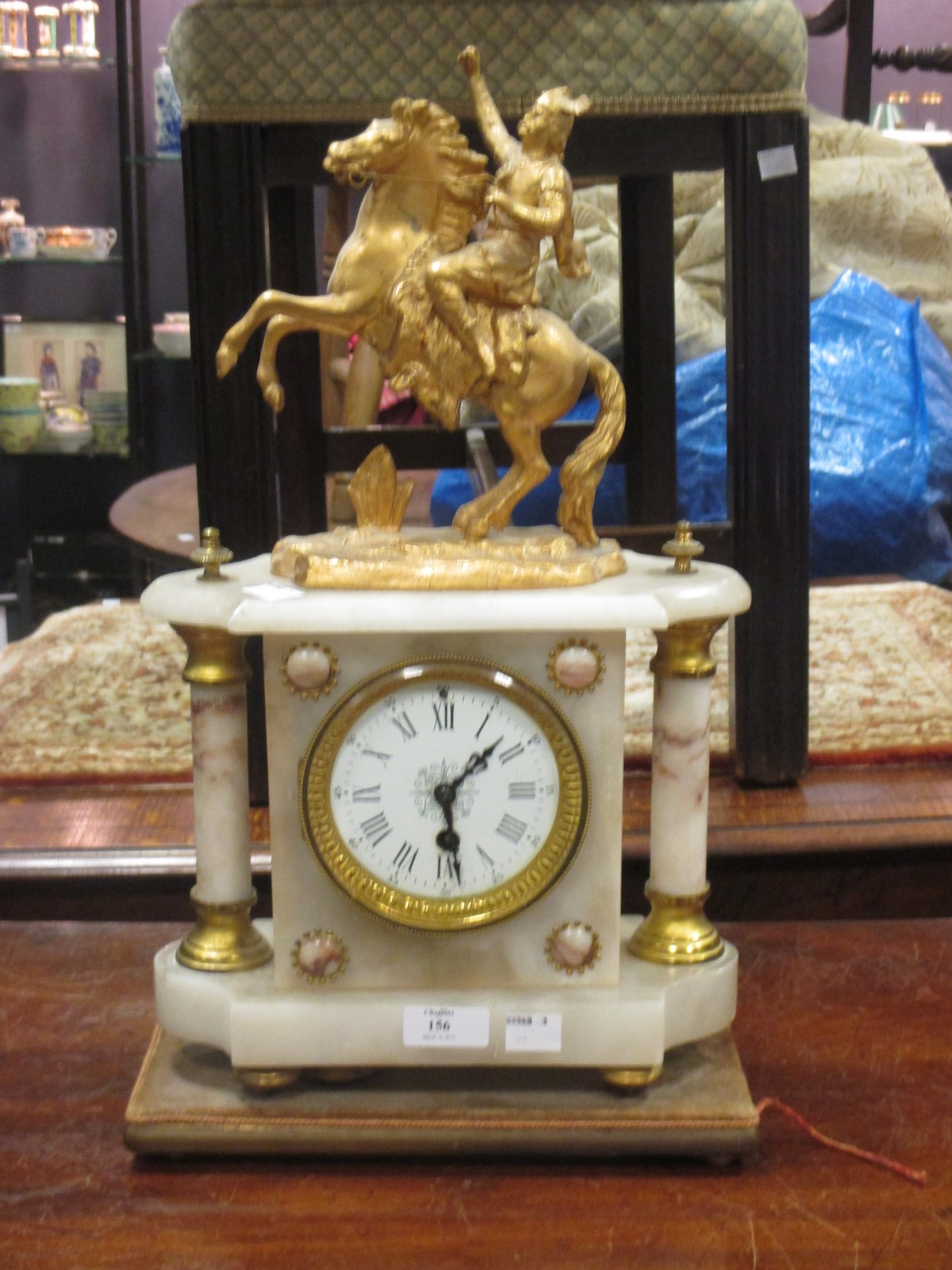 A gilt metal and alabaster mantle clock surmounted with a figure on a rearing horse