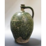 A French green glazed pottery bellarmine shaped jug, possibly 17th century, 37cm high  This has a