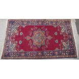 A modern Persian red ground rug with central floral lozenge and carnation emblazoned border, 215 x